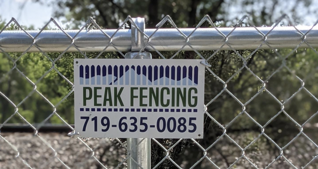Peak Fencing sign mounted on chain link fence